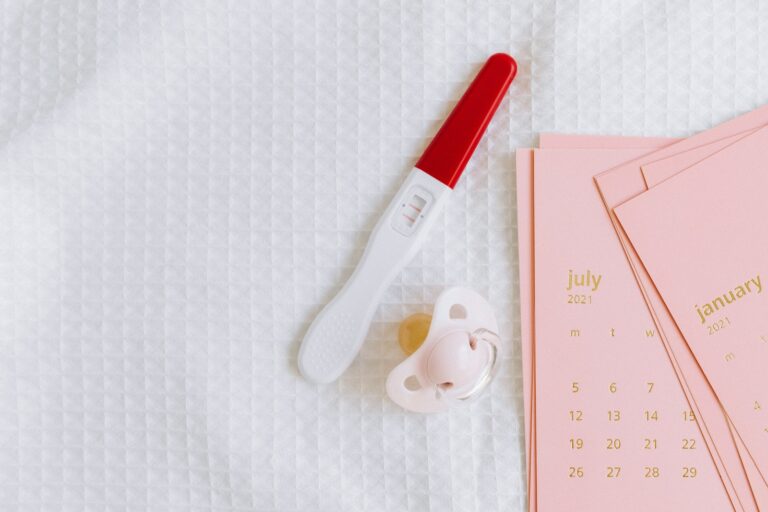 White and Red Pregnancy Test Beside the Pink Pacifier