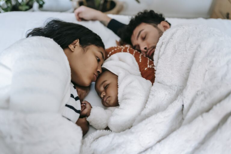 Calm ethnic family sleeping on bed in bedroom